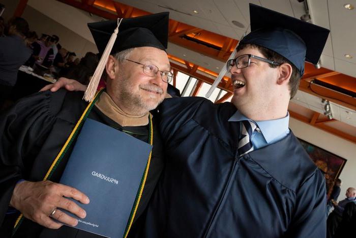 Graduate in cap and gown with a faculty member smiling at each other