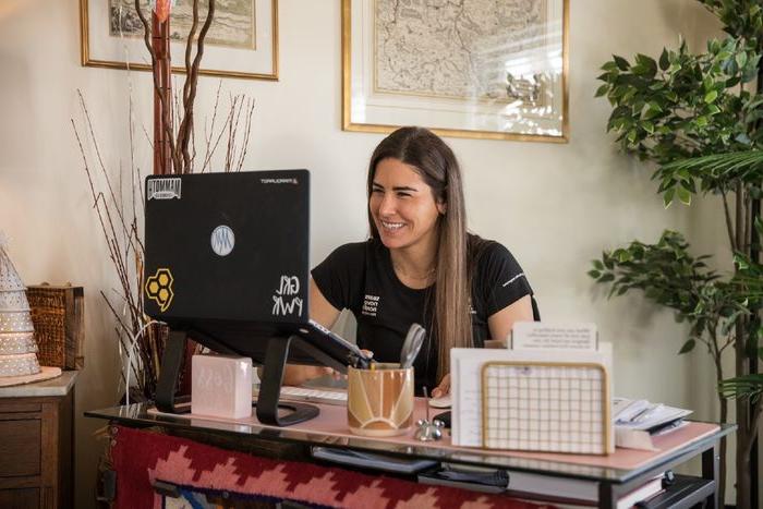 A woman sits at a desk and works on a laptop.