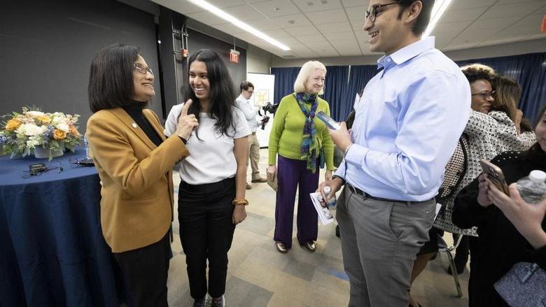 President Bendapudi chats with several students in a room.