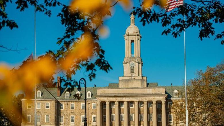 Stone campus building with fall foliage in foreground