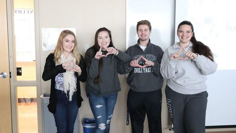 four college students making diamonds with their hands