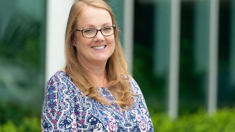 head shot of woman wearing glasses outside office building