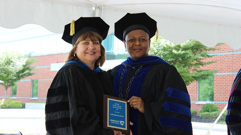 women pose with a plaque