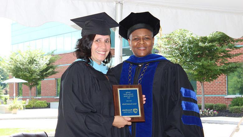 two women pose with a plaque