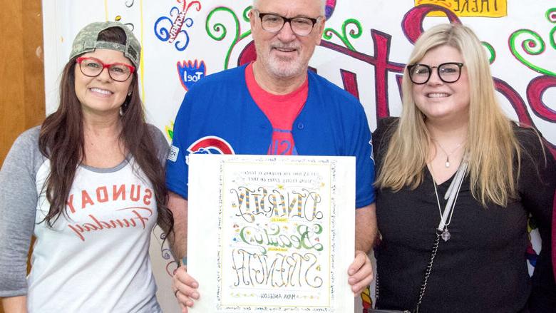 three people pose in front of a mural