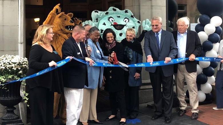 people cutting a blue ribbon with Nittany Lion