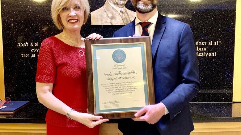 man handing framed award to woman