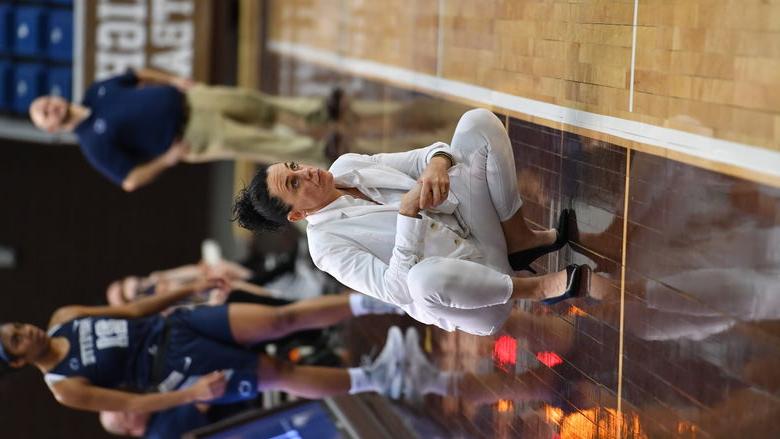 A women squatting on the sideline of a basketball court