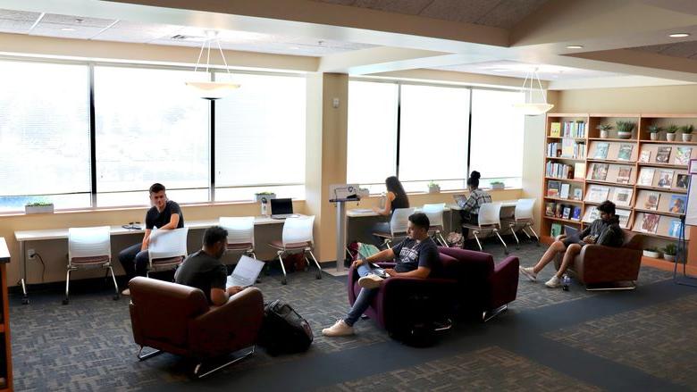 students studying in lounge chairs and desk chairs in library