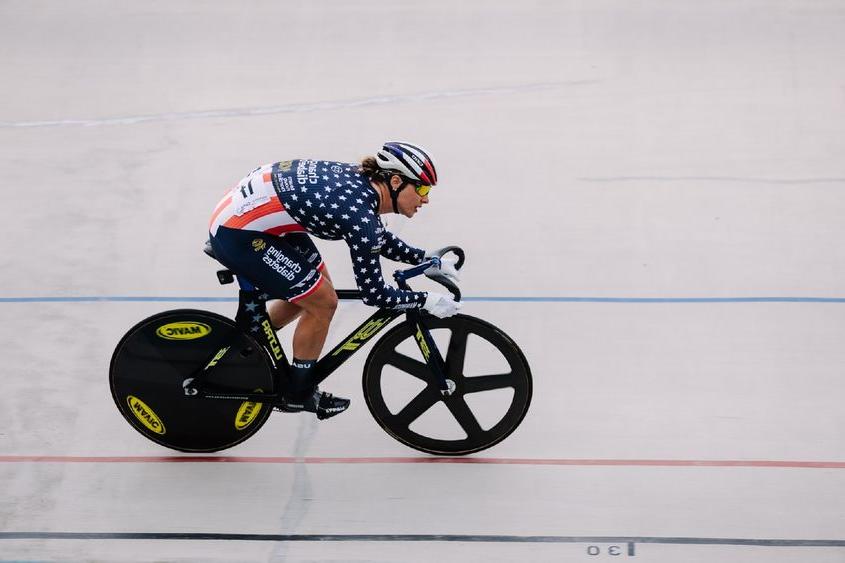 A woman on a bicycle races down a track.