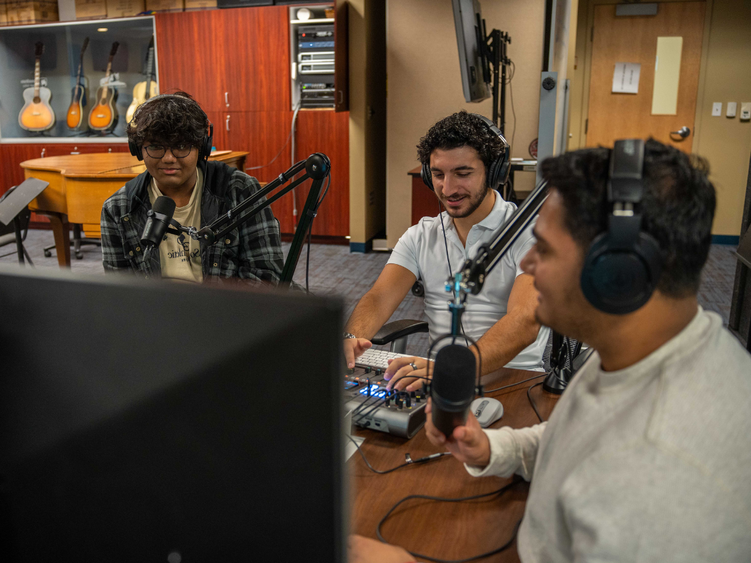 3 male students sitting in a podcasting booth 